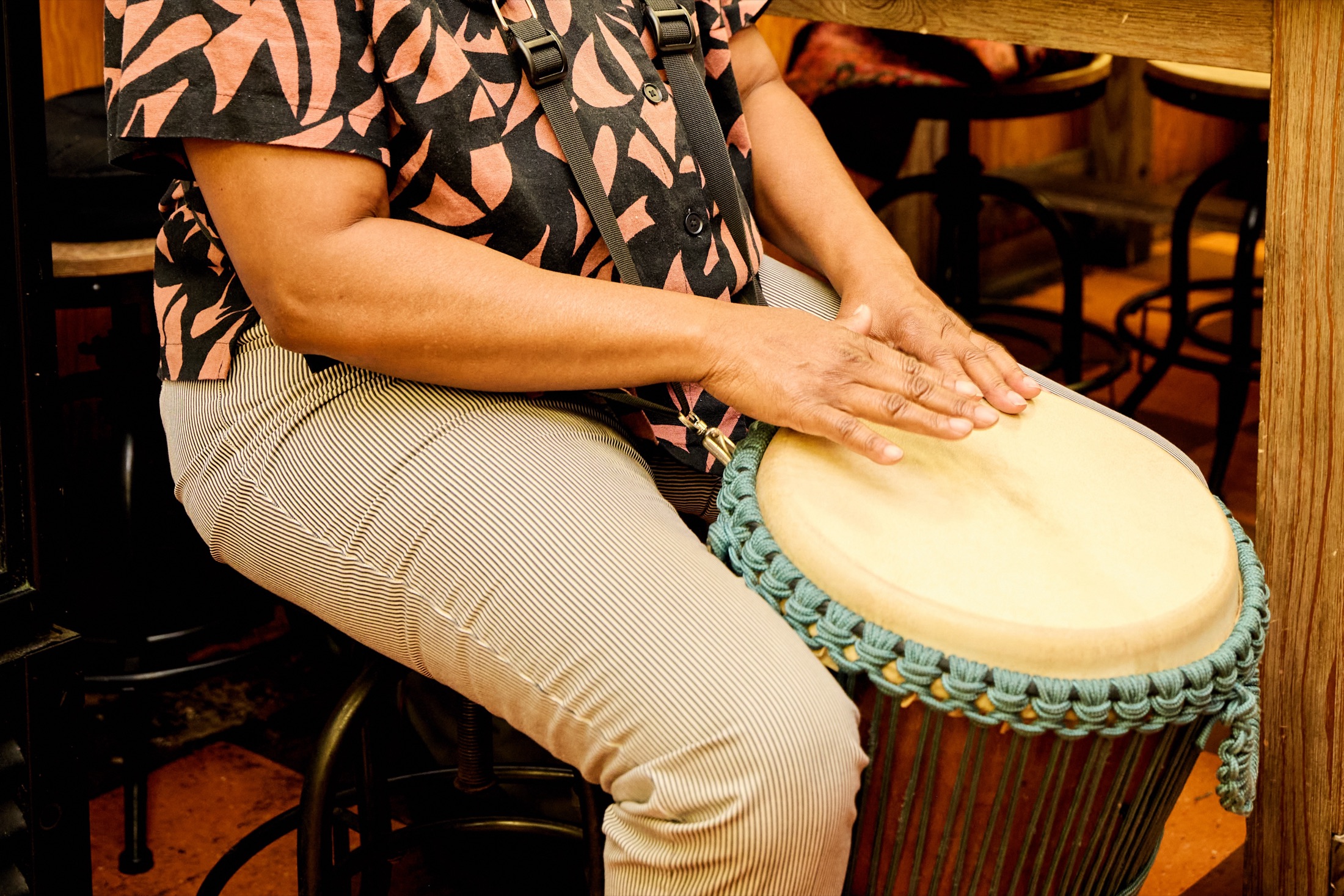 Close-up of a drummer's hands resting on the head of a djembe.